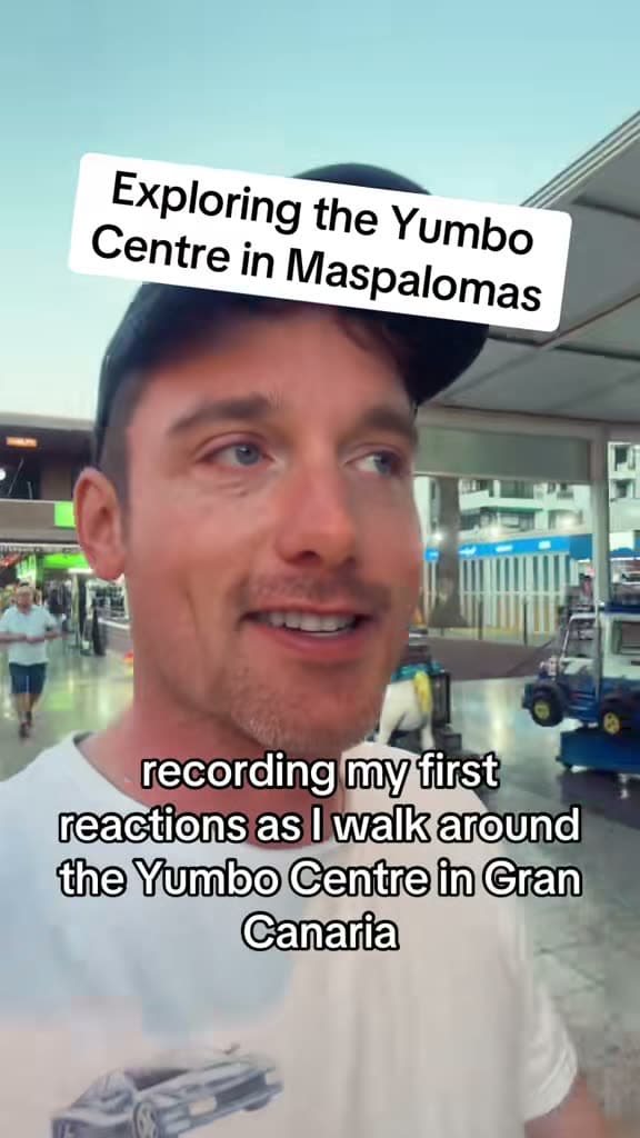Christopher Adams in a cap by a shopping centre; the title card reads Exploring the Yumbo Centre in Maspalomas