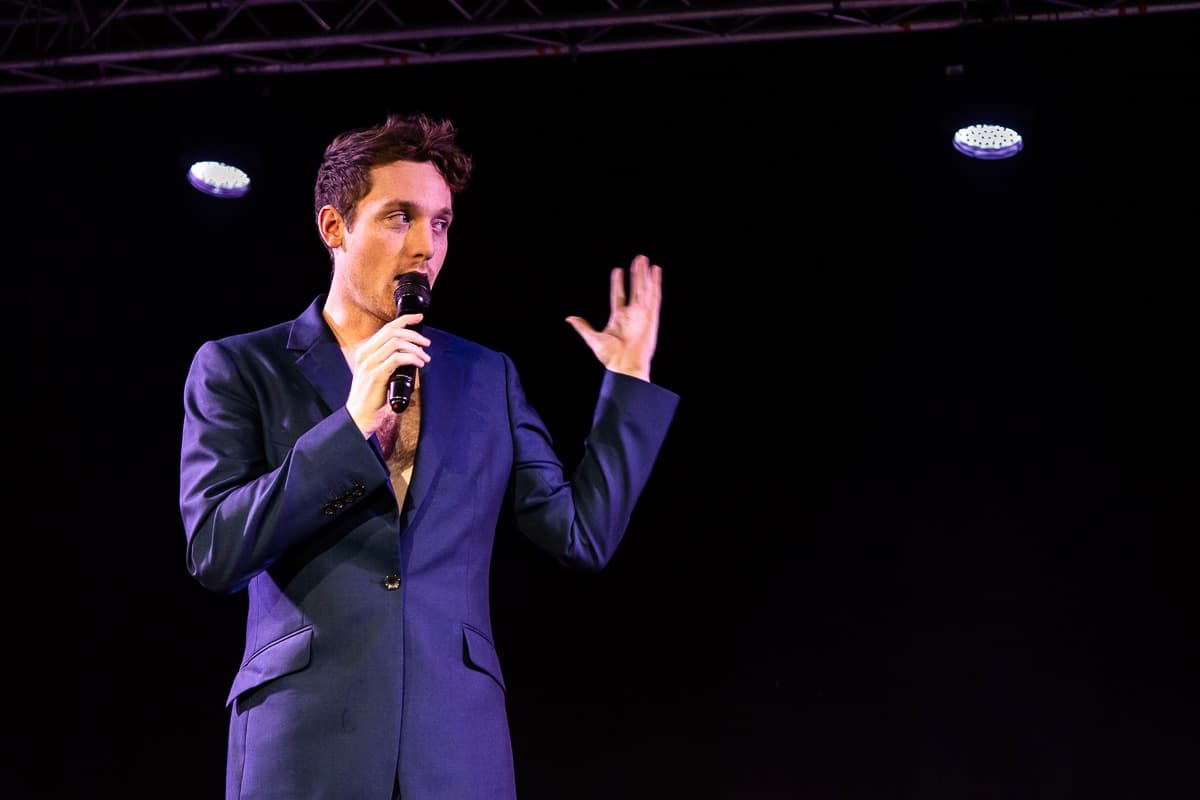 Christopher Adams presenting on stage with a microphone
