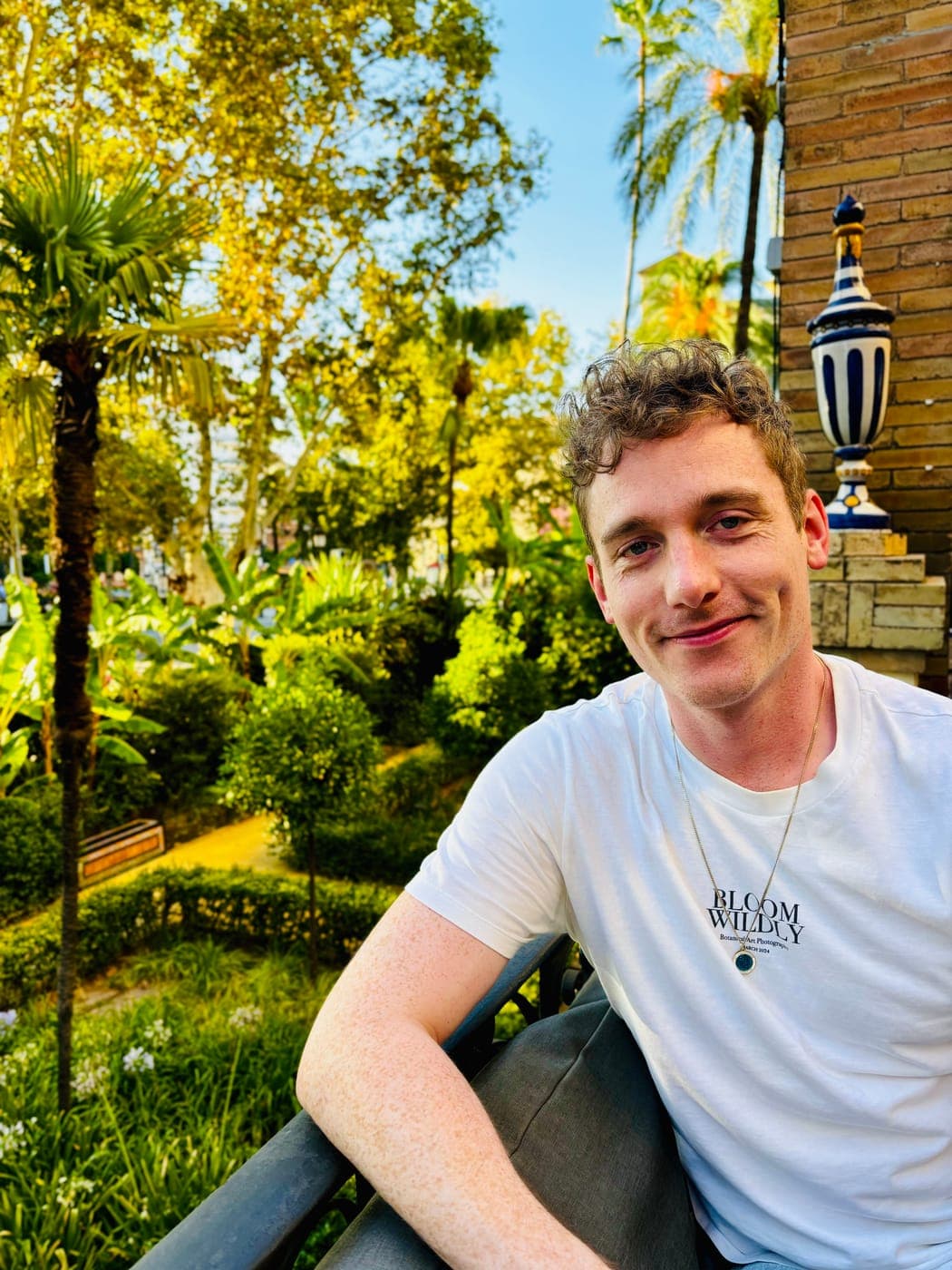 Christopher Adams leaning on a railing in a garden of palms