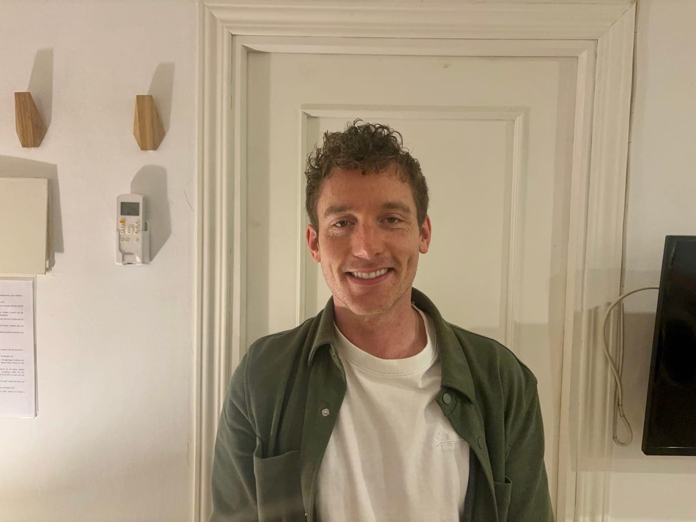 Christopher Adams smiling in a doorway, green overshirt